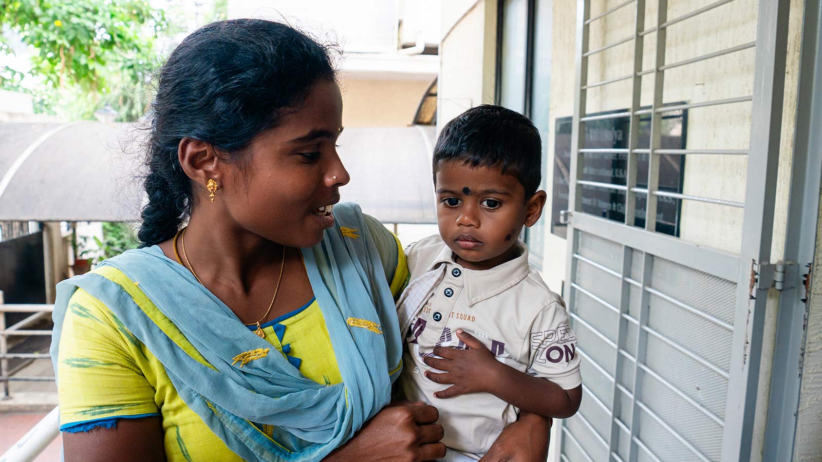 a mother holding her child prepares to drop him off at a migrant daycare