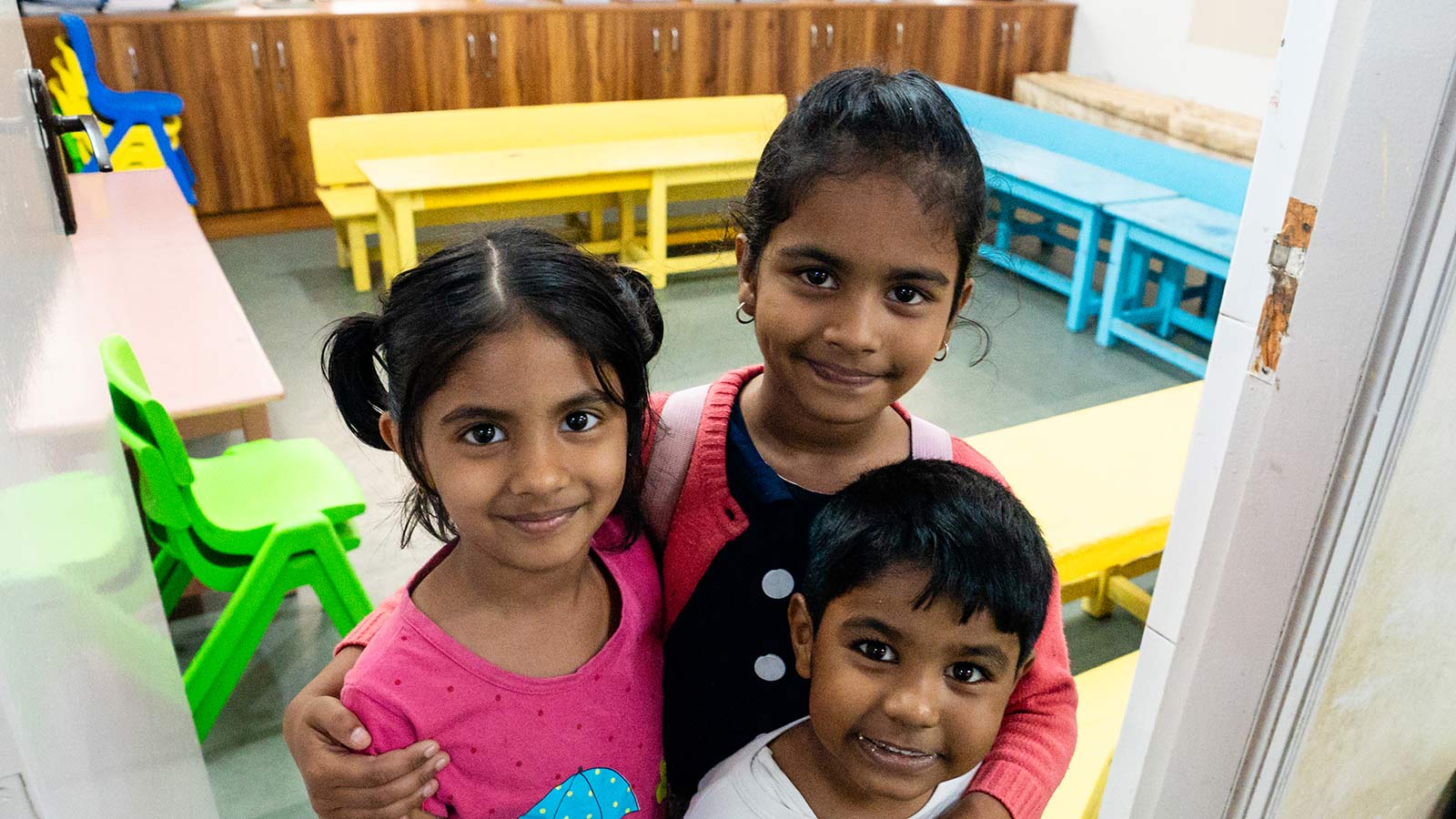 a group of siblings smiles outside their classroom at a migrant daycare