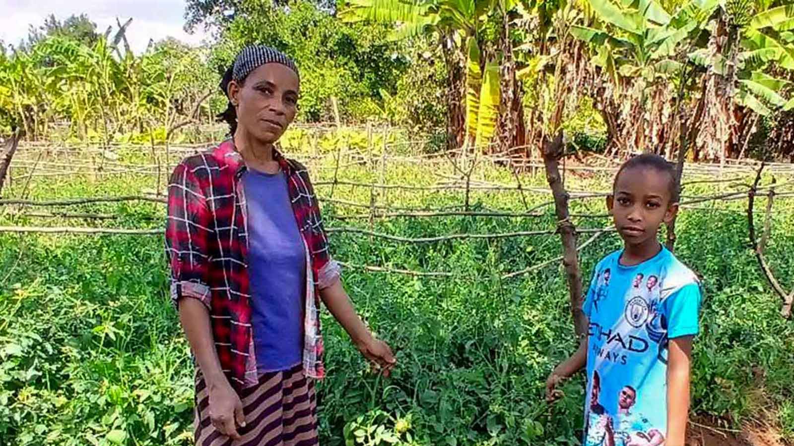 a mom and her daughter pick vegetables from their garden — a gift of hope from a donor