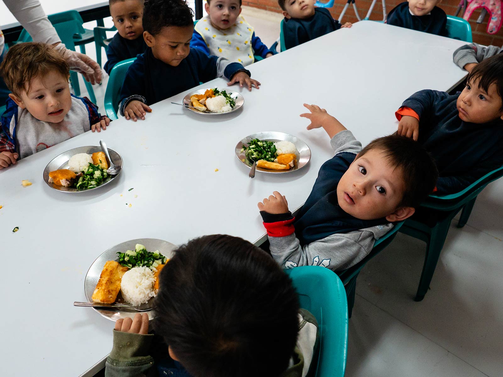 a group of children sit at a table with a plate of lunch in a daycare program