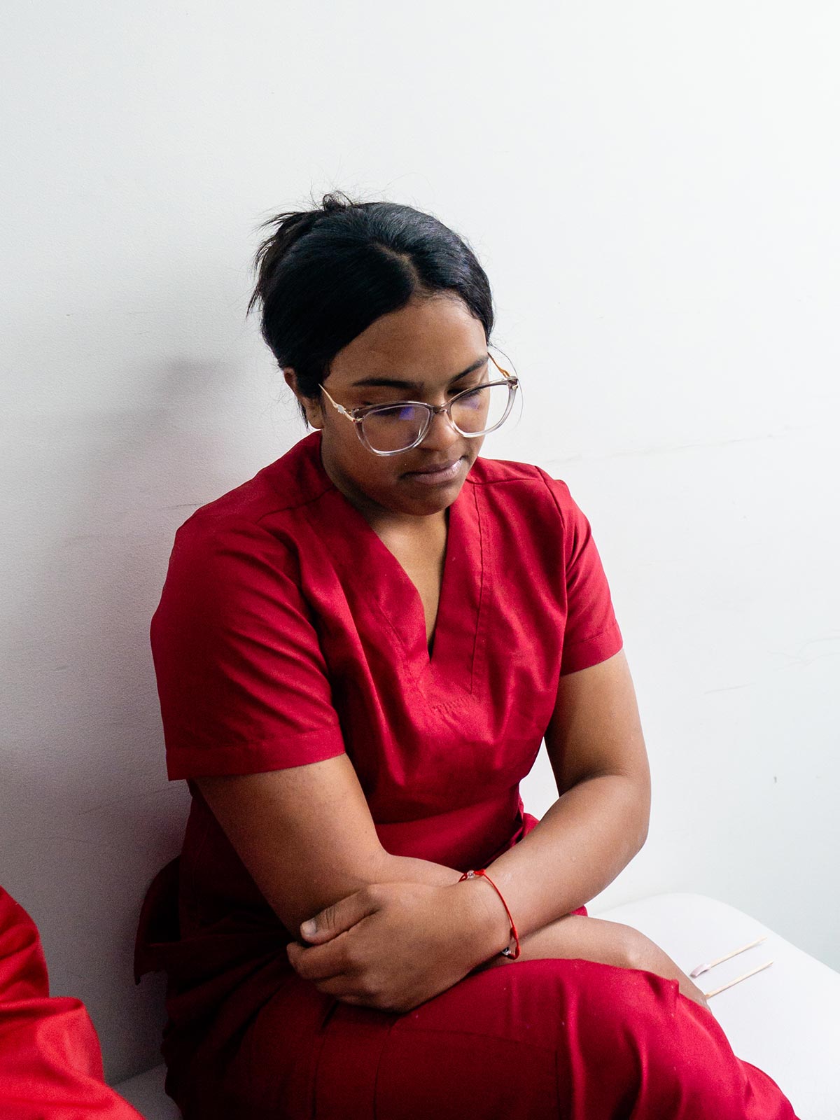 a young woman wearing red scrubs tells her story with a sober expression.