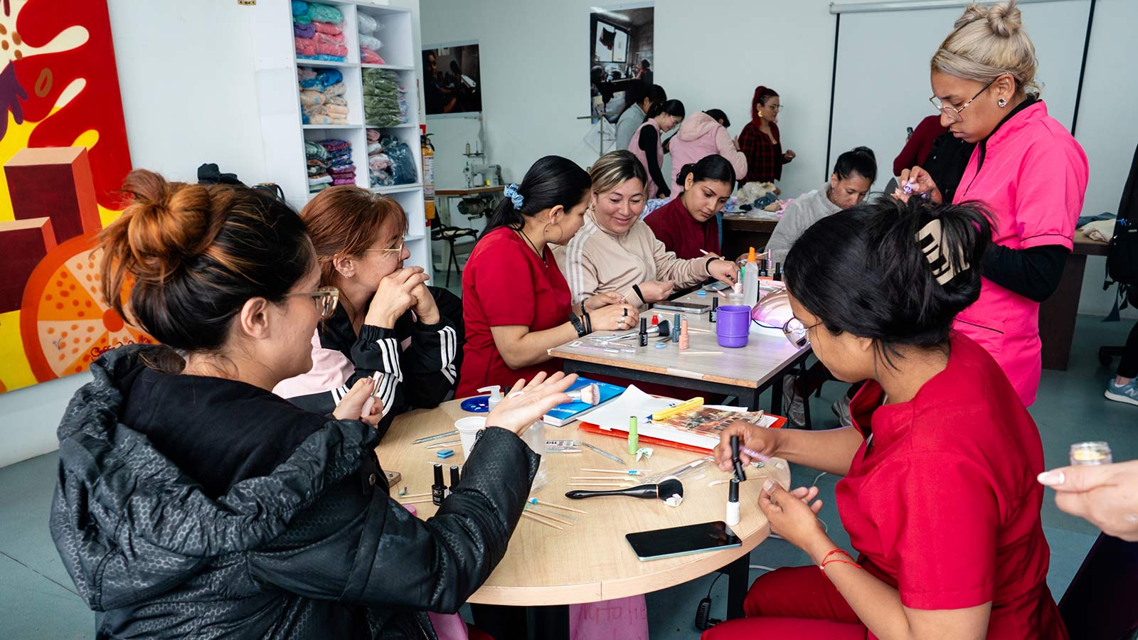 A group of women practice nail art at Bambi. In the background are sewing machines.