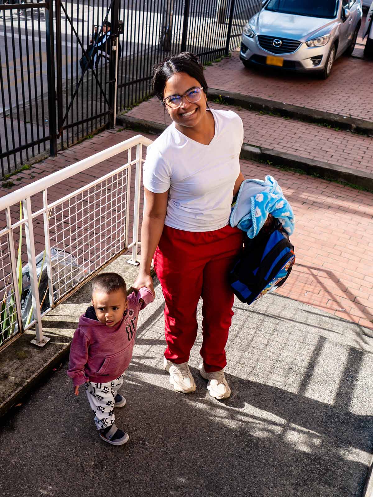 a young mom picks up her son from daycare, holding his hand