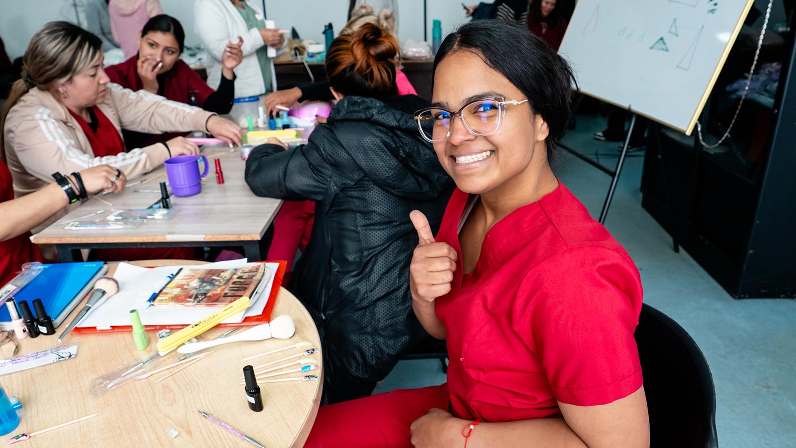 a mom who received a gift of hope gives a thumbs up and a smile as she practices nail art skills