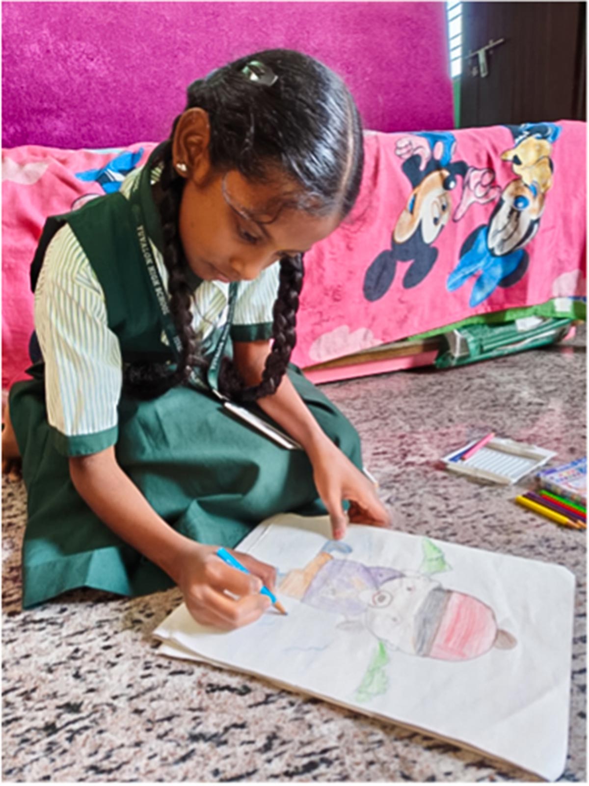 a girl in braids and a school uniform draws a colorful picture on the tile floor