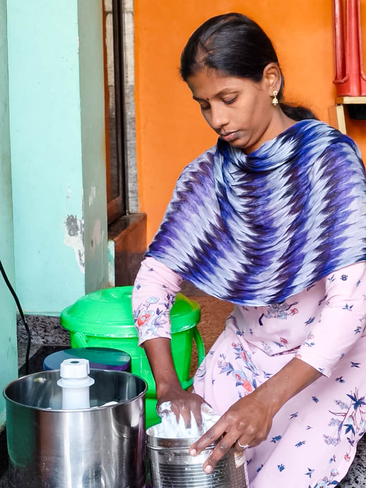 a mom mixes dosa batter with her hands to sell to her community