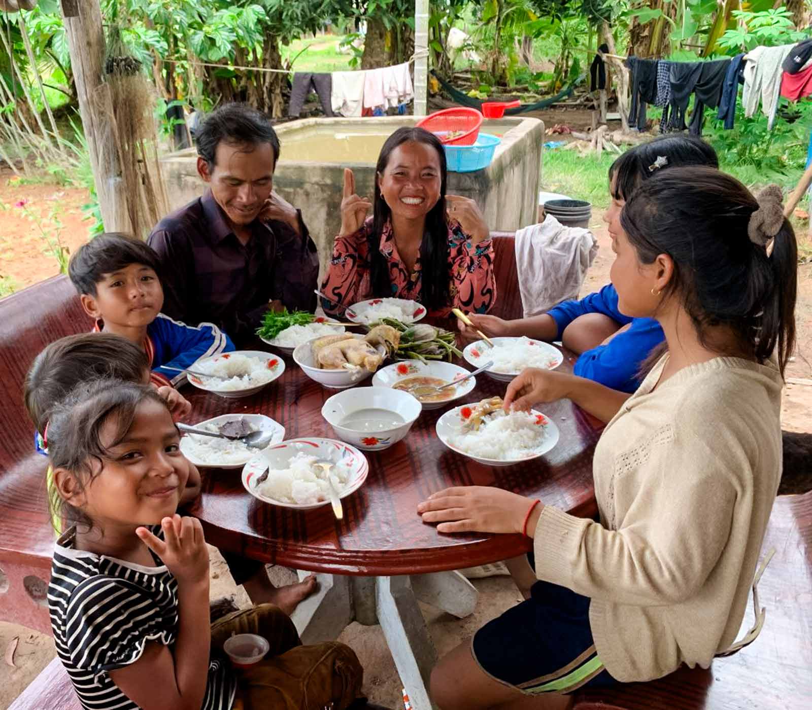 a family of seven sits at a table and eats a meal together