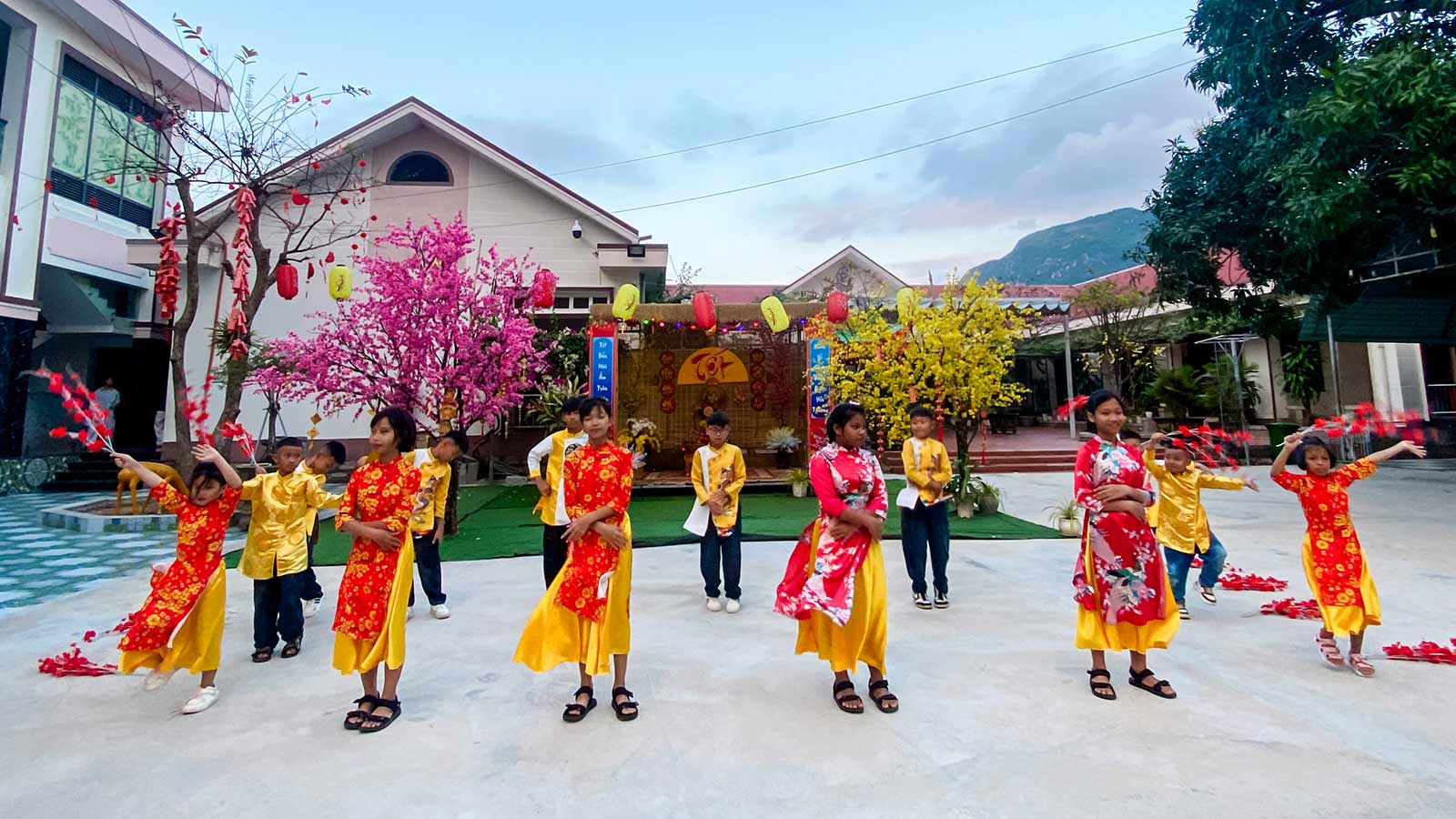 a group of children wearing yellow and red perform a traditional dance for tet in vietnam