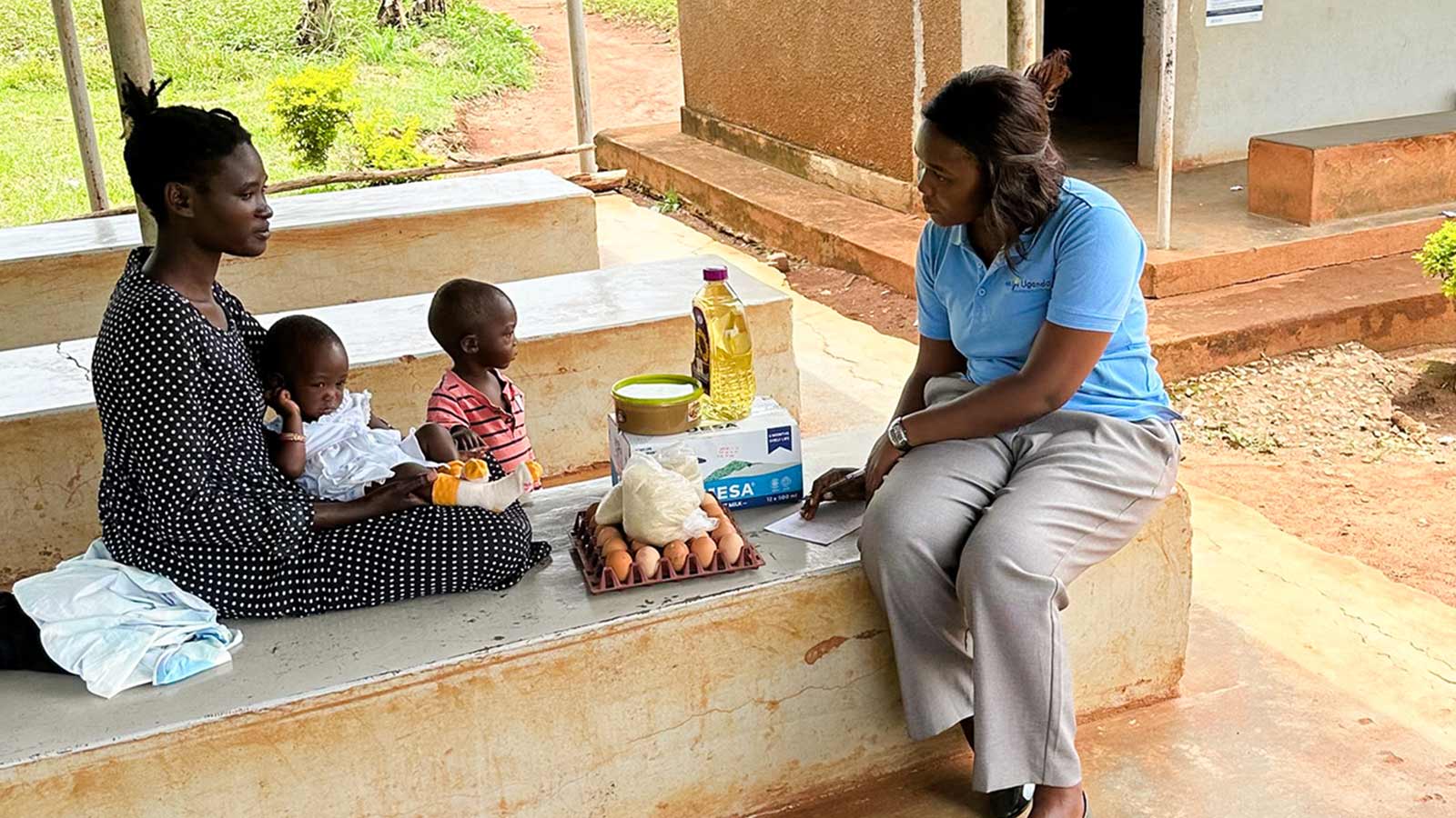 a mom receives emergency food rations from a Holt Uganda staff member