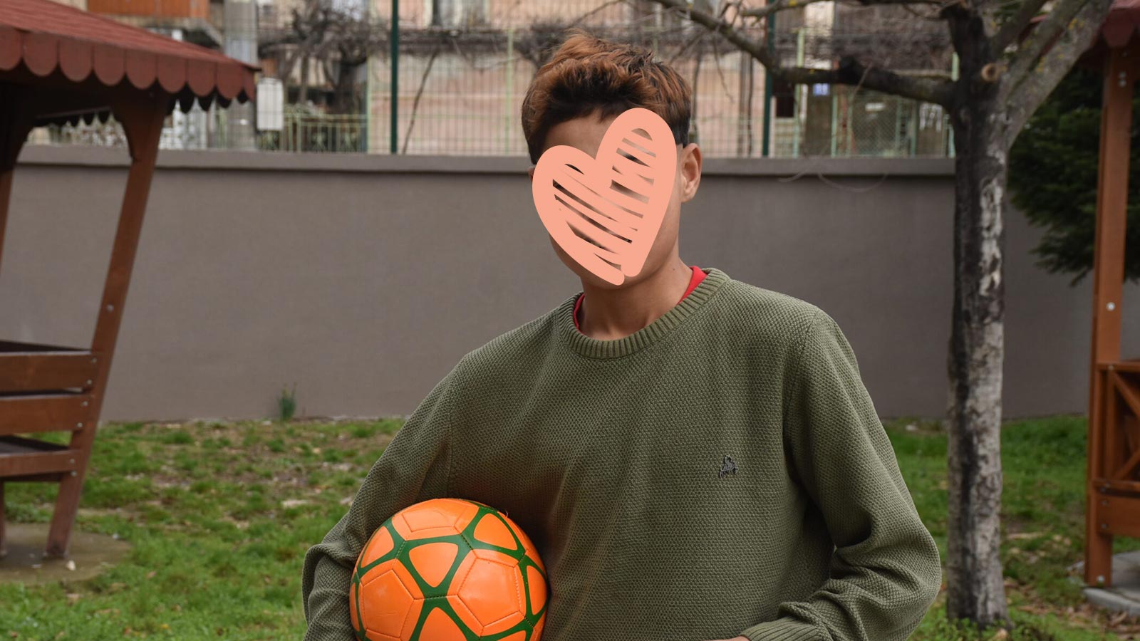 a boy with a heart over his face holds a soccer ball