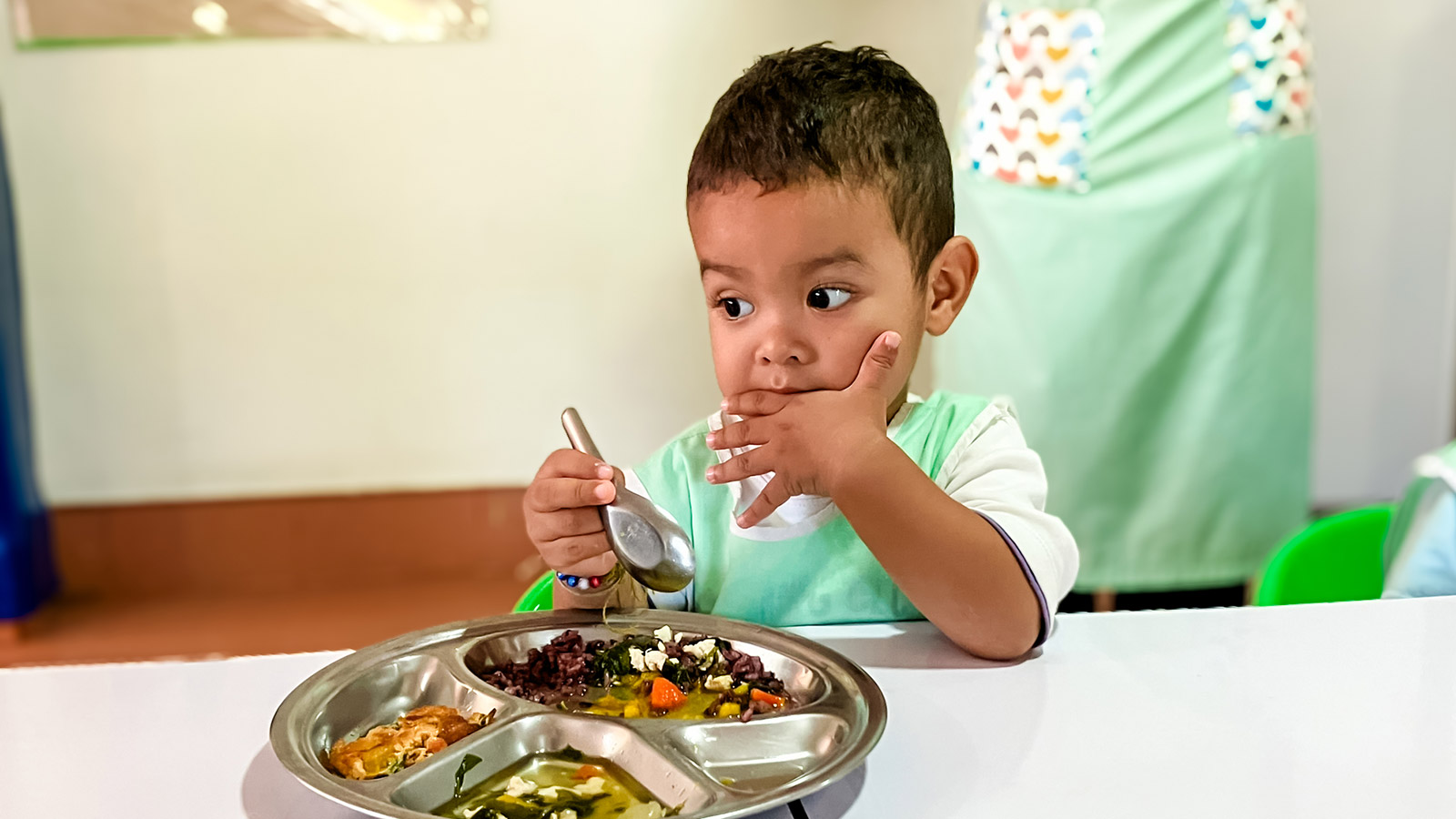 a little boy in Thailand eats his lunch at daycare