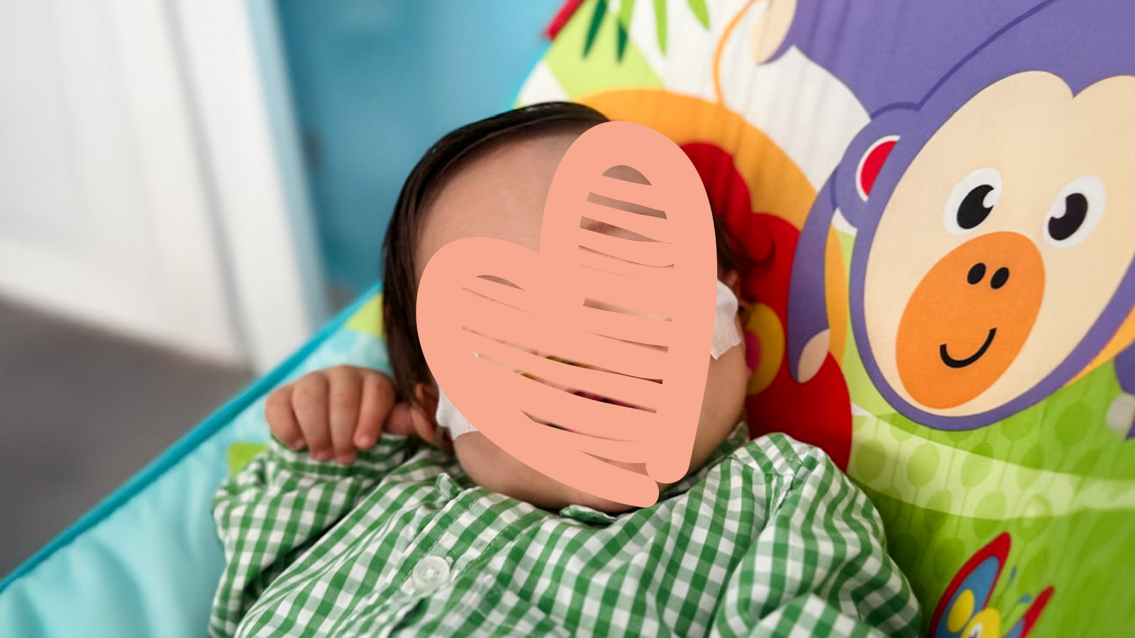 a little baby boy lays in a bouncy chair with a heart over his face