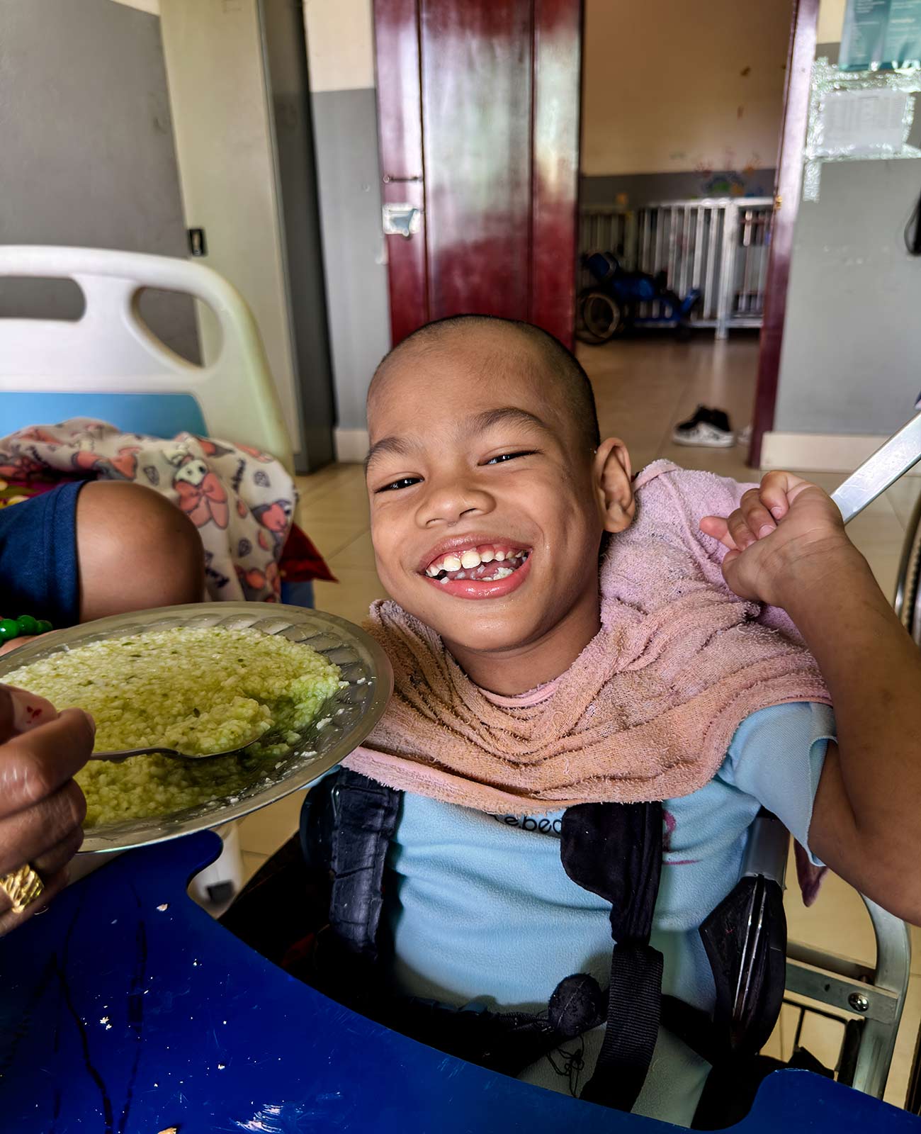 a child with special needs smiles and is fed a nutritious meal