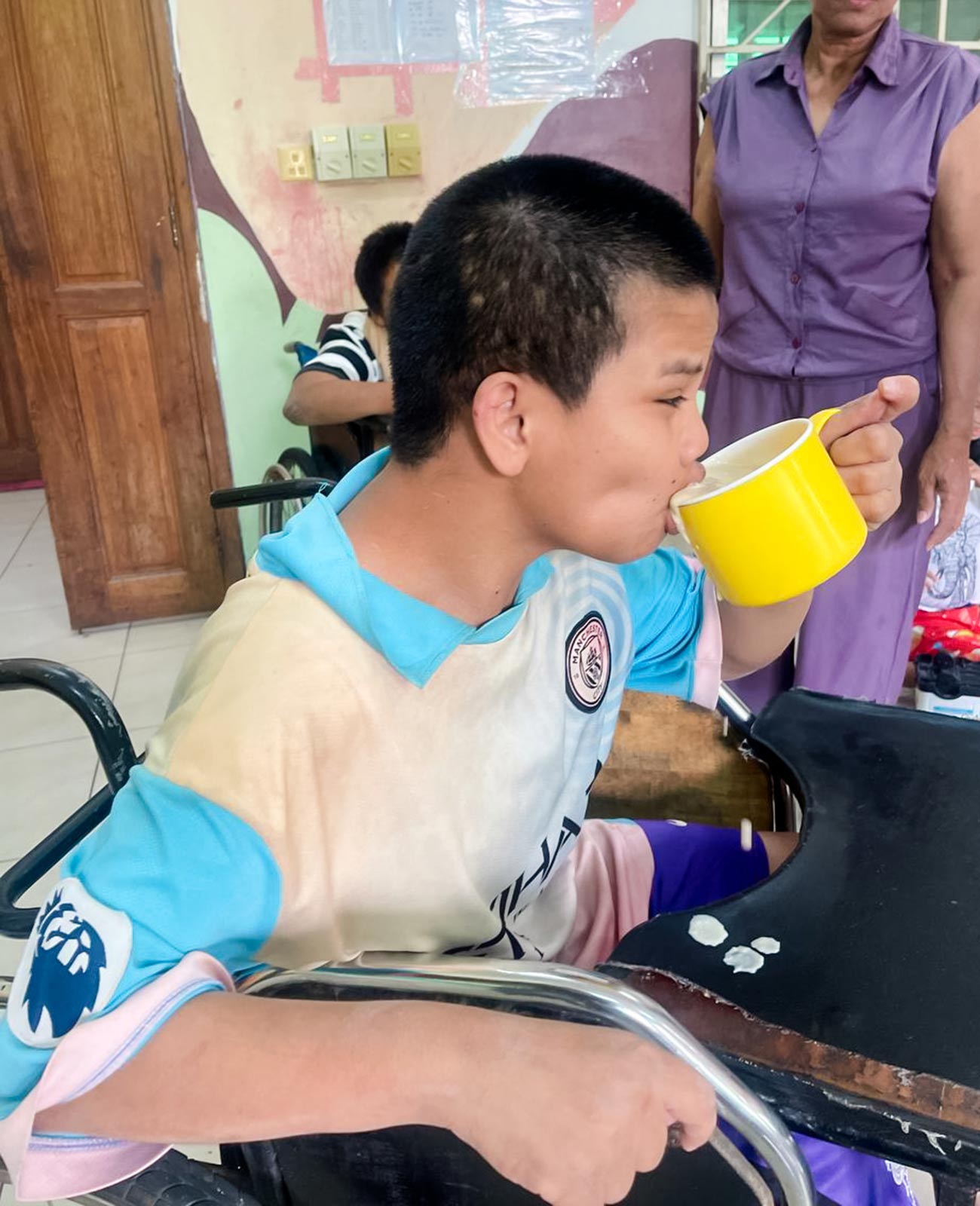 a child with special needs feeds himself with a cup