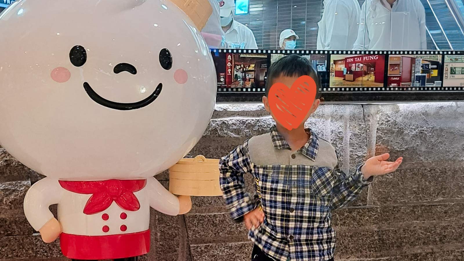 a boy with a heart over his face wears a flannel shirt and poses next to a cartoon chef