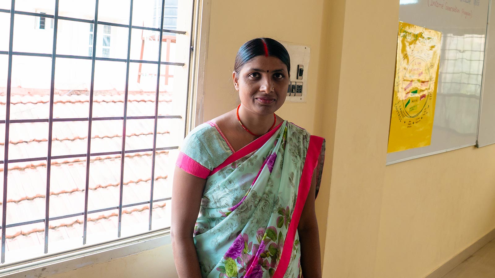 a woman in a floral sari stands in a women's center in Southern India