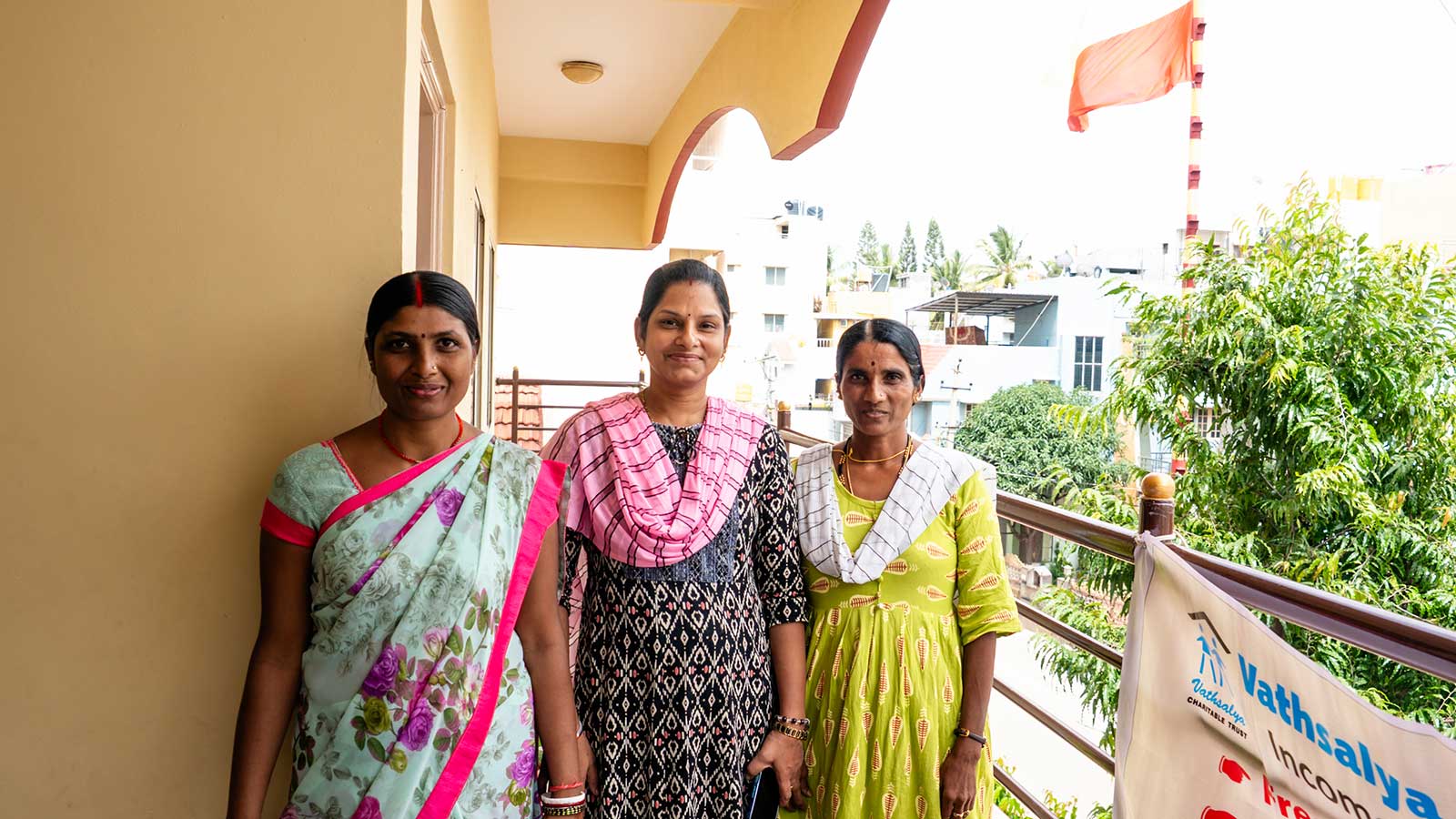 a group of women stand outside a women's center for skills training in India