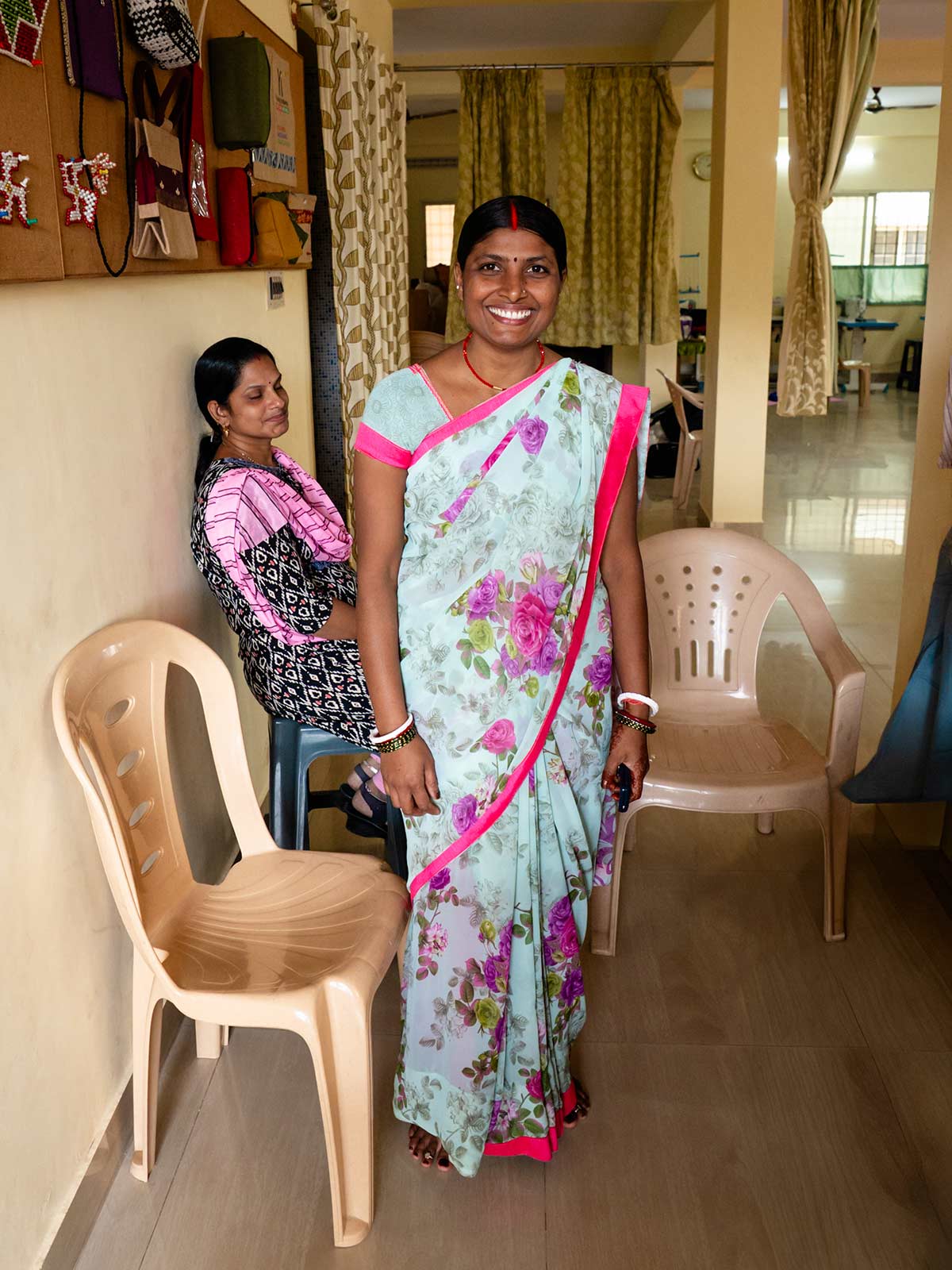 a woman in a floral sari smiles and stands in a women's center in Southern India