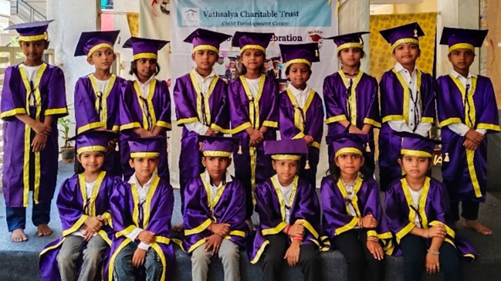 a group of children stand with purple graduation caps and gowns, celebrating preschool graduation in India