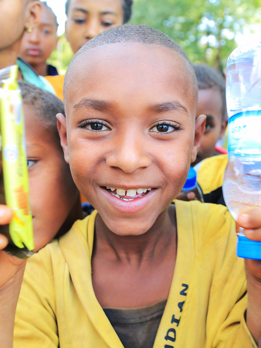 a boy in a yellow shirt smiles at a birthday celebration in Ethiopia