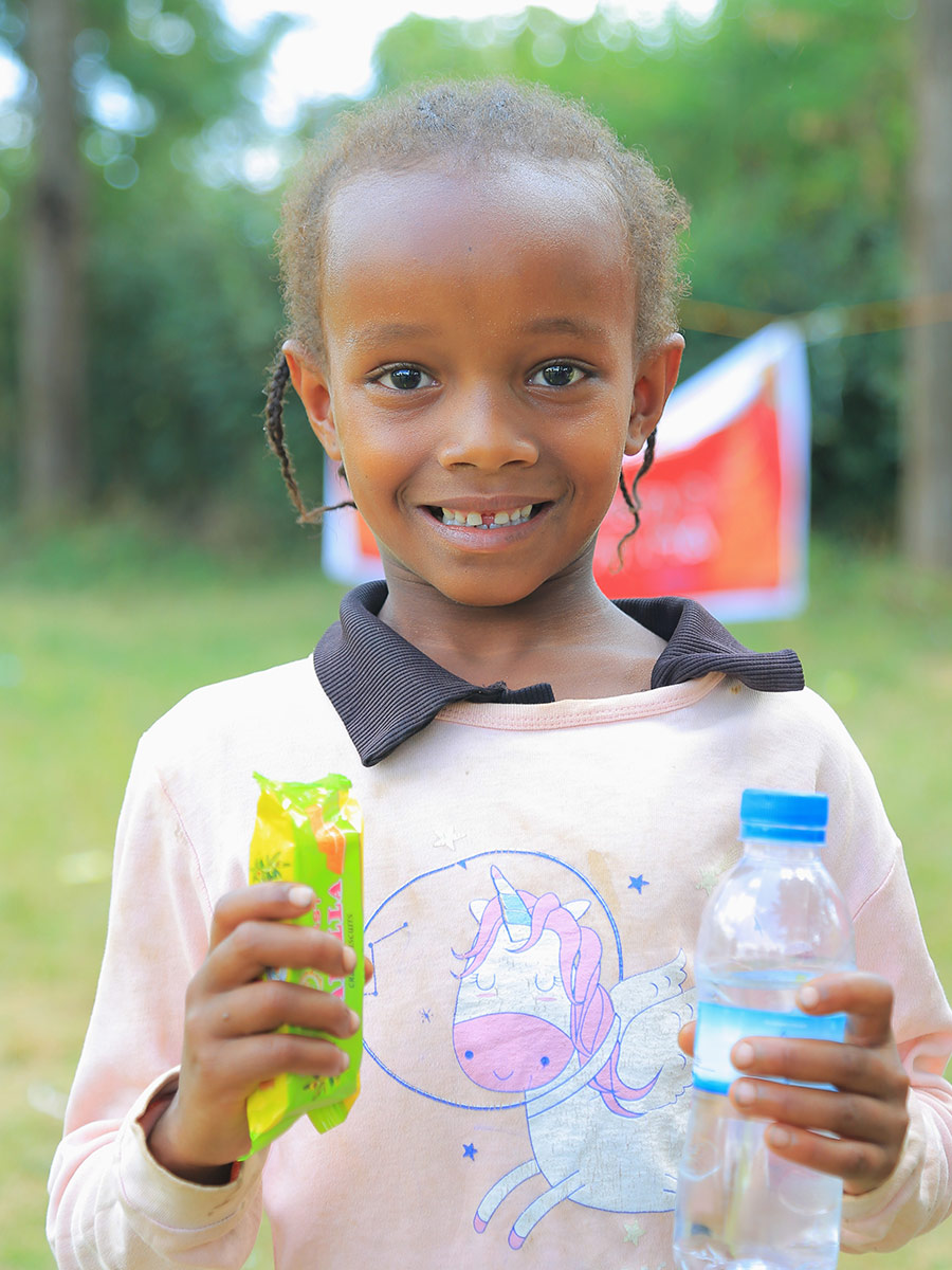 a girl in a pink shirt smiles at a birthday celebration in Ethiopia