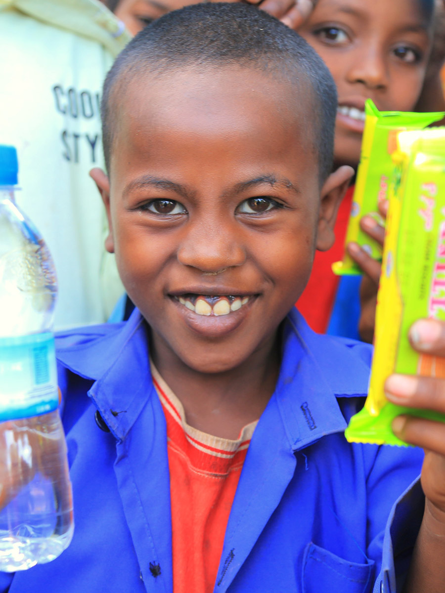 a boy in a blue shirt smiles at a birthday celebration in Ethiopia