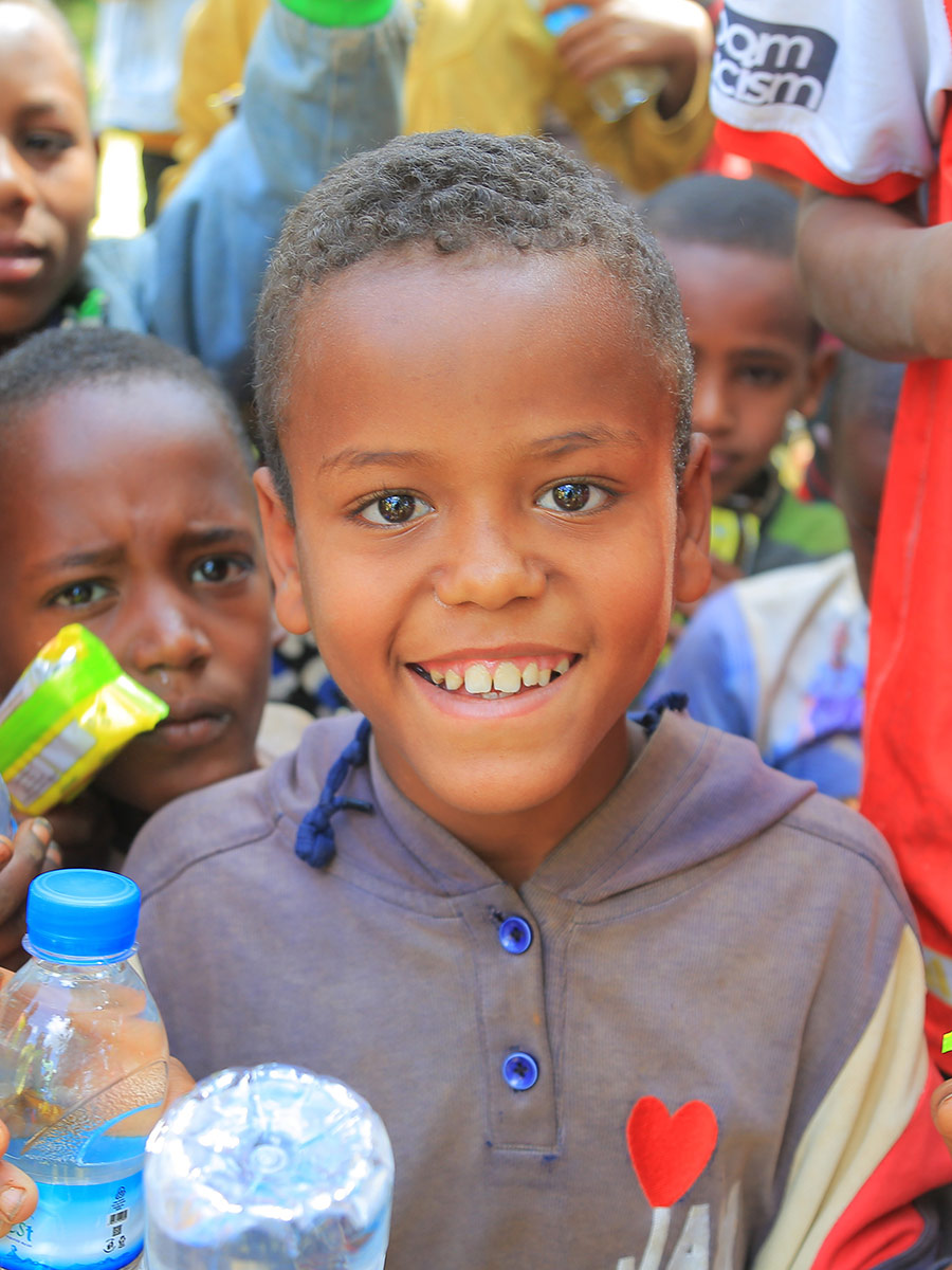 a boy in a grey shirt smiles at a birthday celebration in Ethiopia