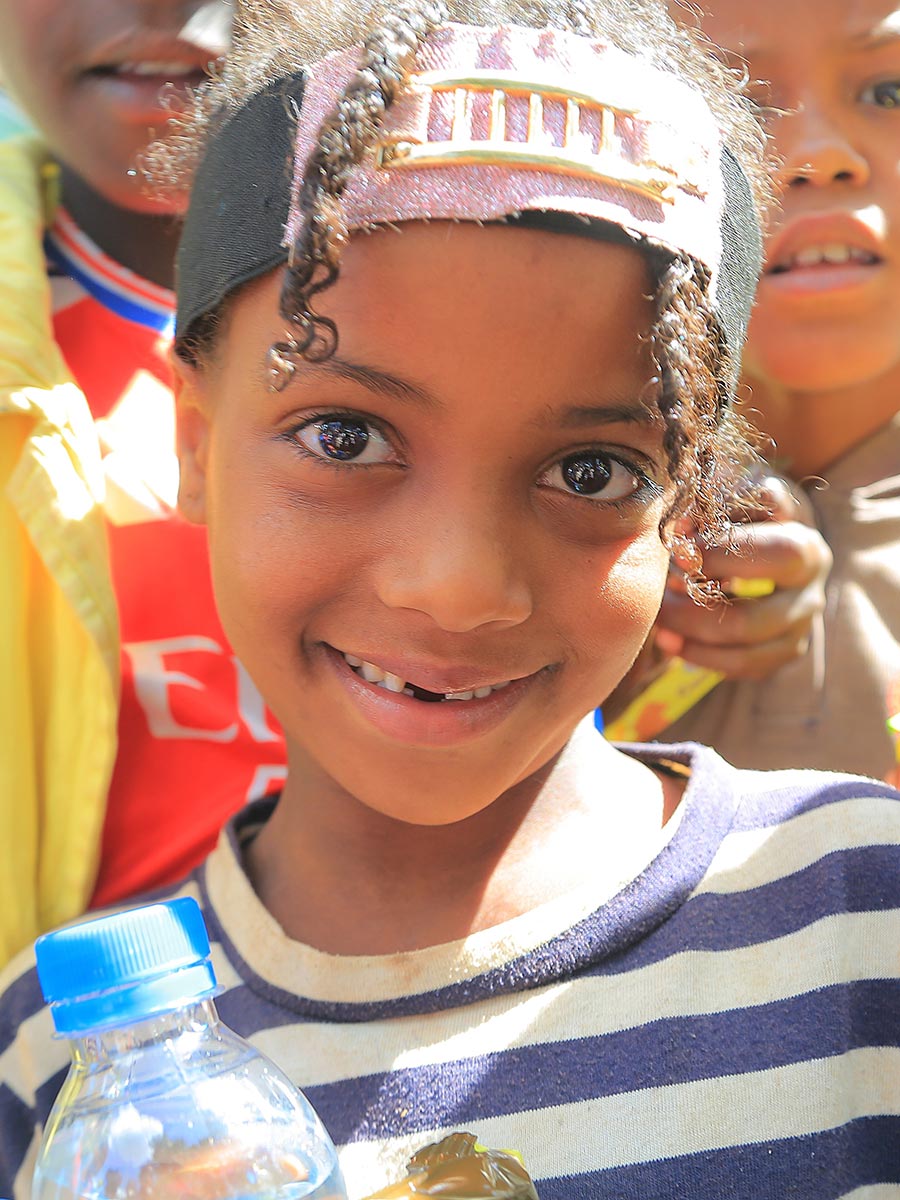 a girl in a striped shirt smiles at a birthday celebration in Ethiopia