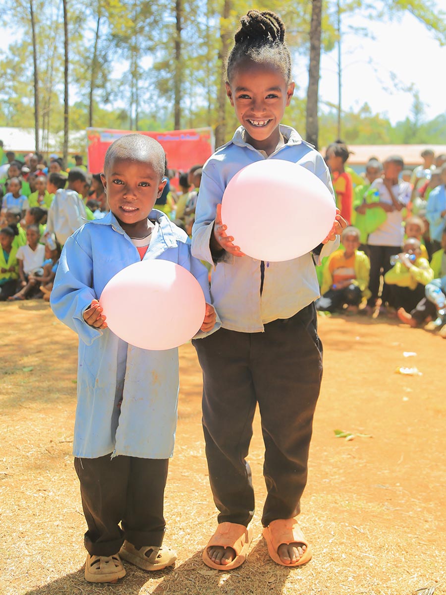 two children hold balloons at a celebration in Ethiopia