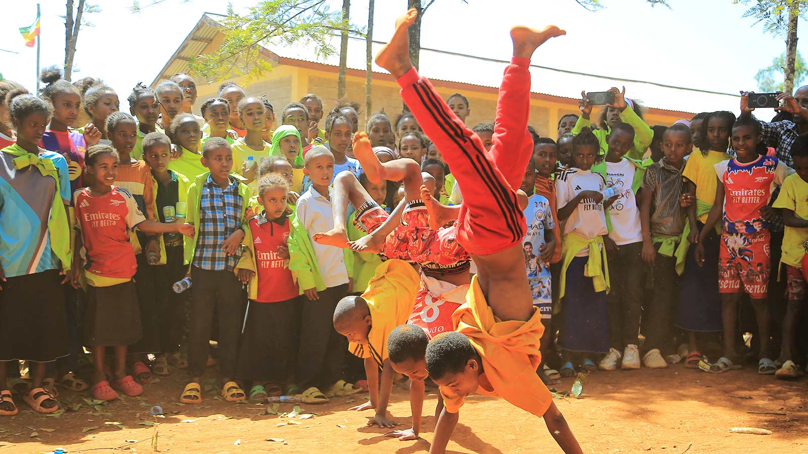 three boys perform acrobatics at a celebration in Ethiopia, walking on their hands