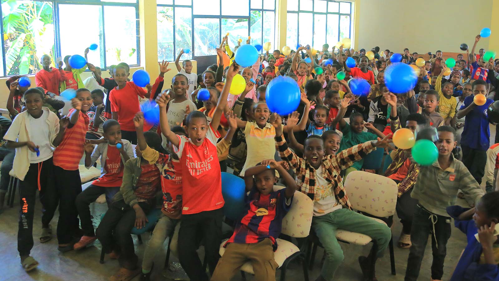 a group of children hold up balloons at a celebration in Ethiopia