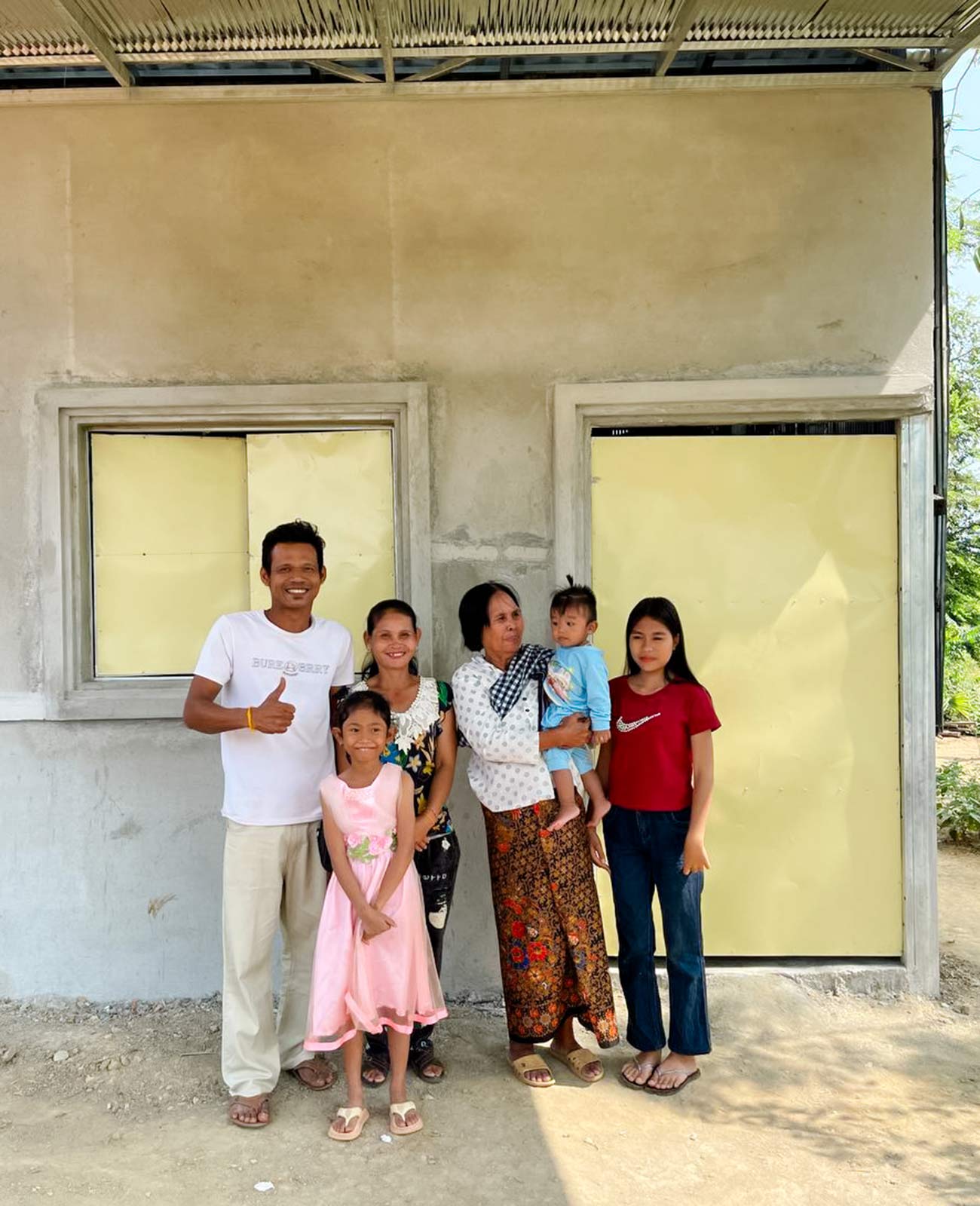 Thida and her family stand outside their new home together