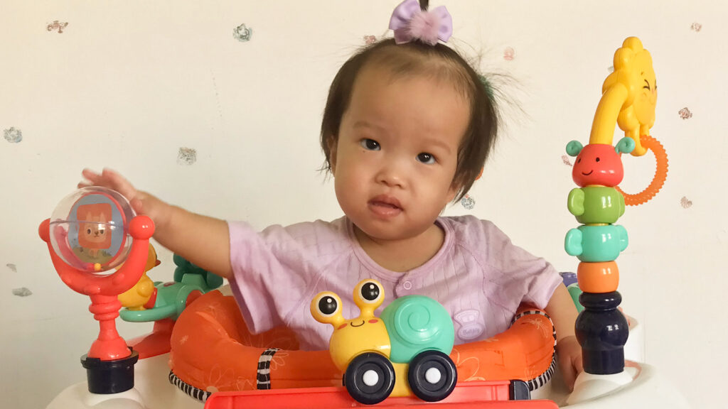 Sweet little girl playing in an exersaucer toy.