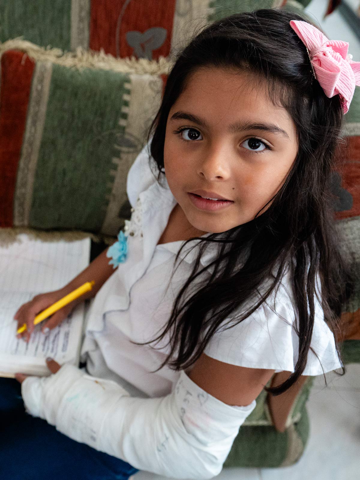a girl with an arm cast writes in her school notebook