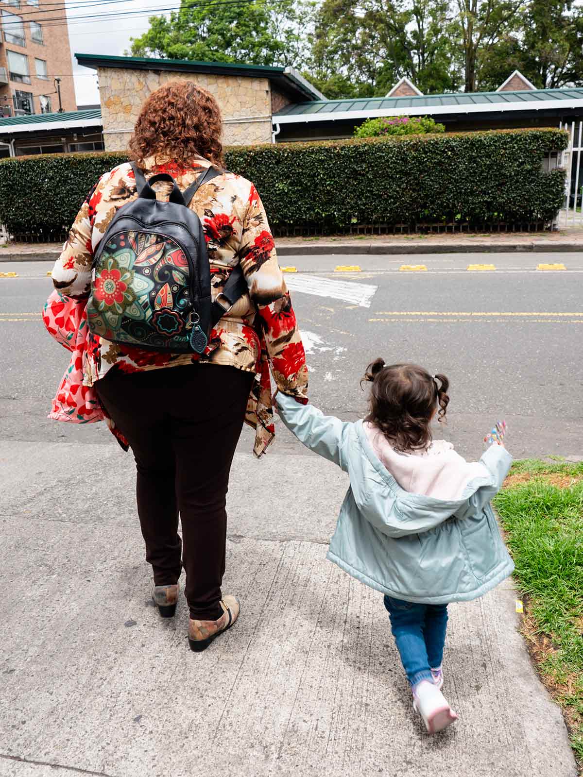 a grandmother holds her granddaughter's hand as they leave La Casa de la Madre y el Niño