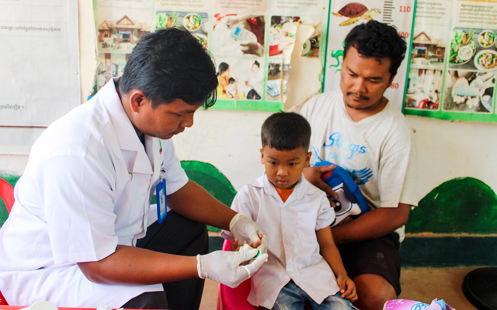 a little boy's arm measurement is taken during a CNP health screening in Cambodia