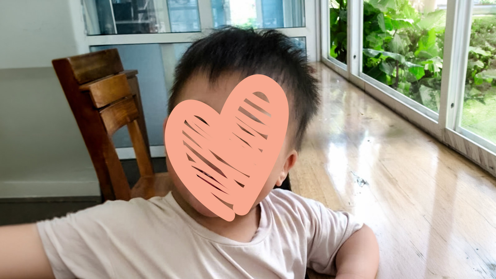 a boy in a white t-shirt and a heart over his face is waiting for adoption