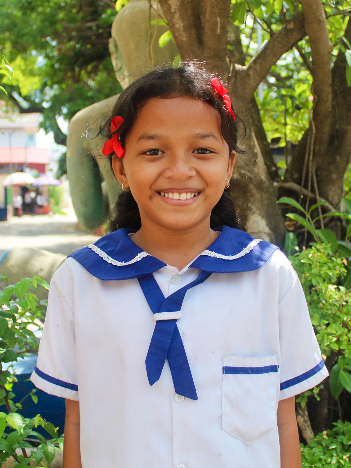 a sponsored girl in Cambodia wears her blue and white school uniform and smiles
