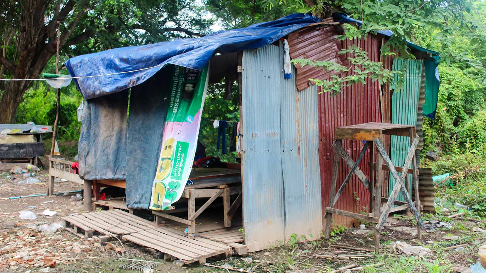 a family's makeshift house in Cambodia, made with tarps and metal sheets