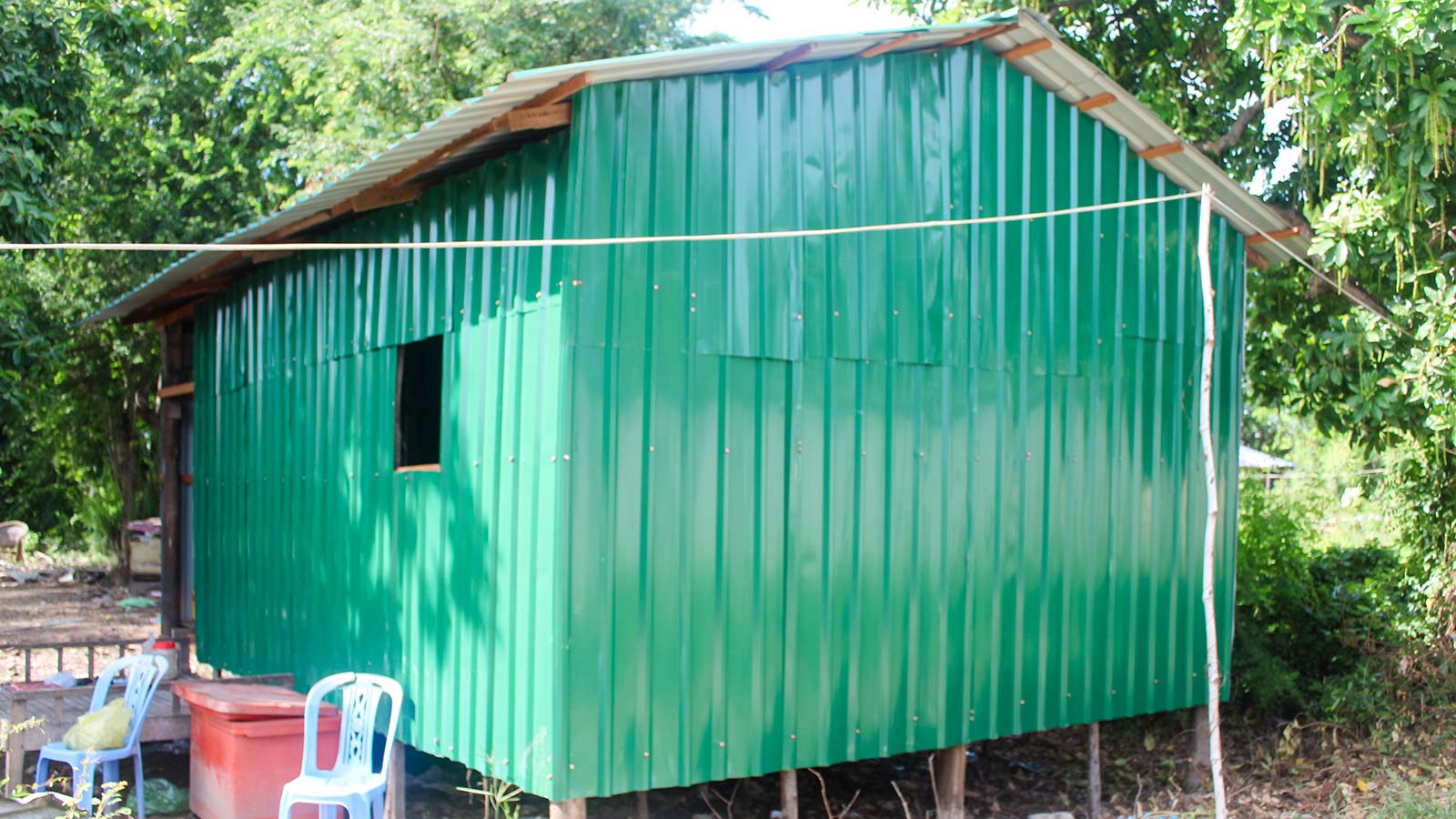 a family's remodeled home with green metal siding in Cambodia