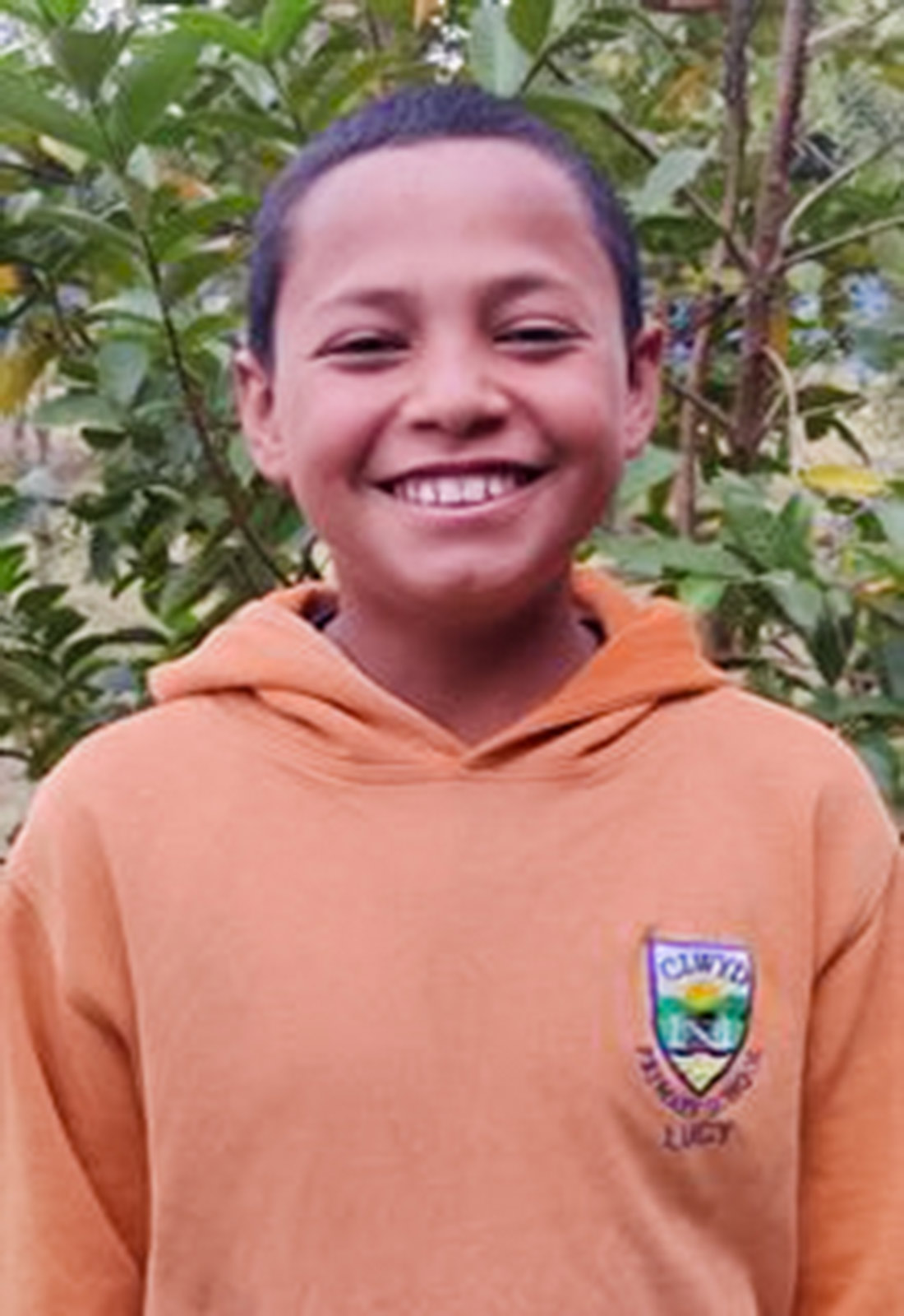 a sponsored boy in an orange sweatshirt smiles into the camera