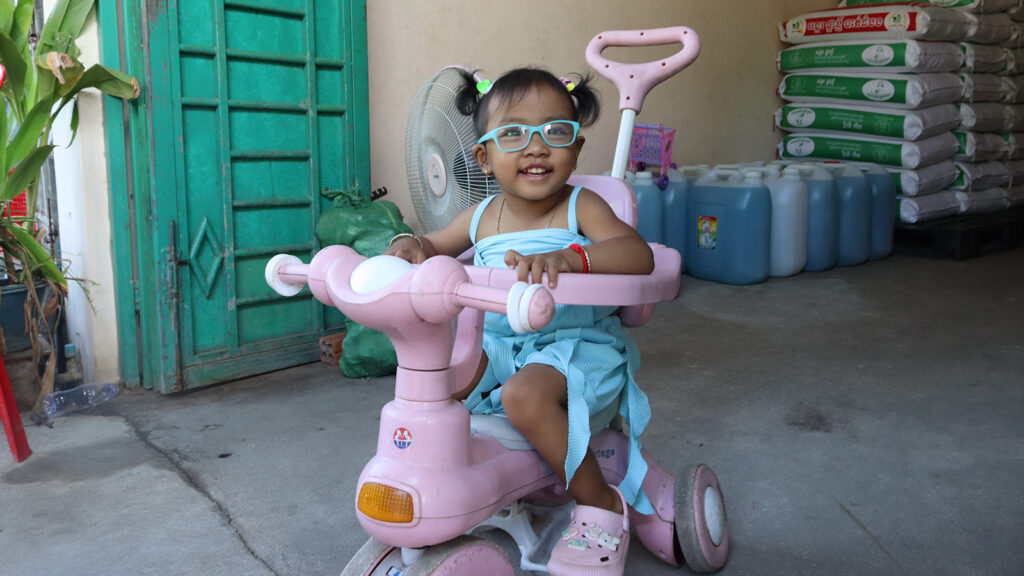 Sophea, a child in special needs foster care in Cambodia, rides her scooter.