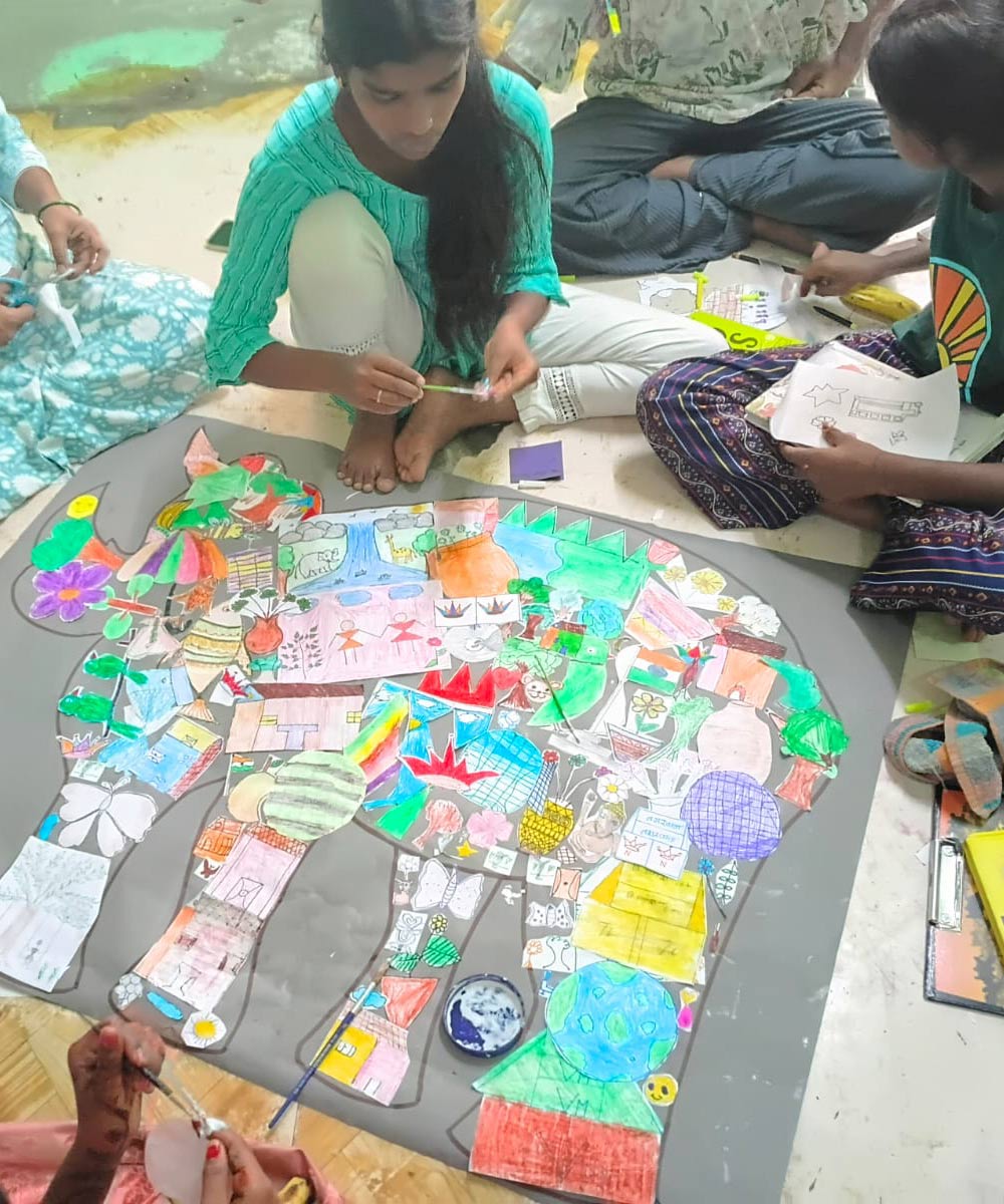 children sit in a circle on the floor and color at summer camp in India