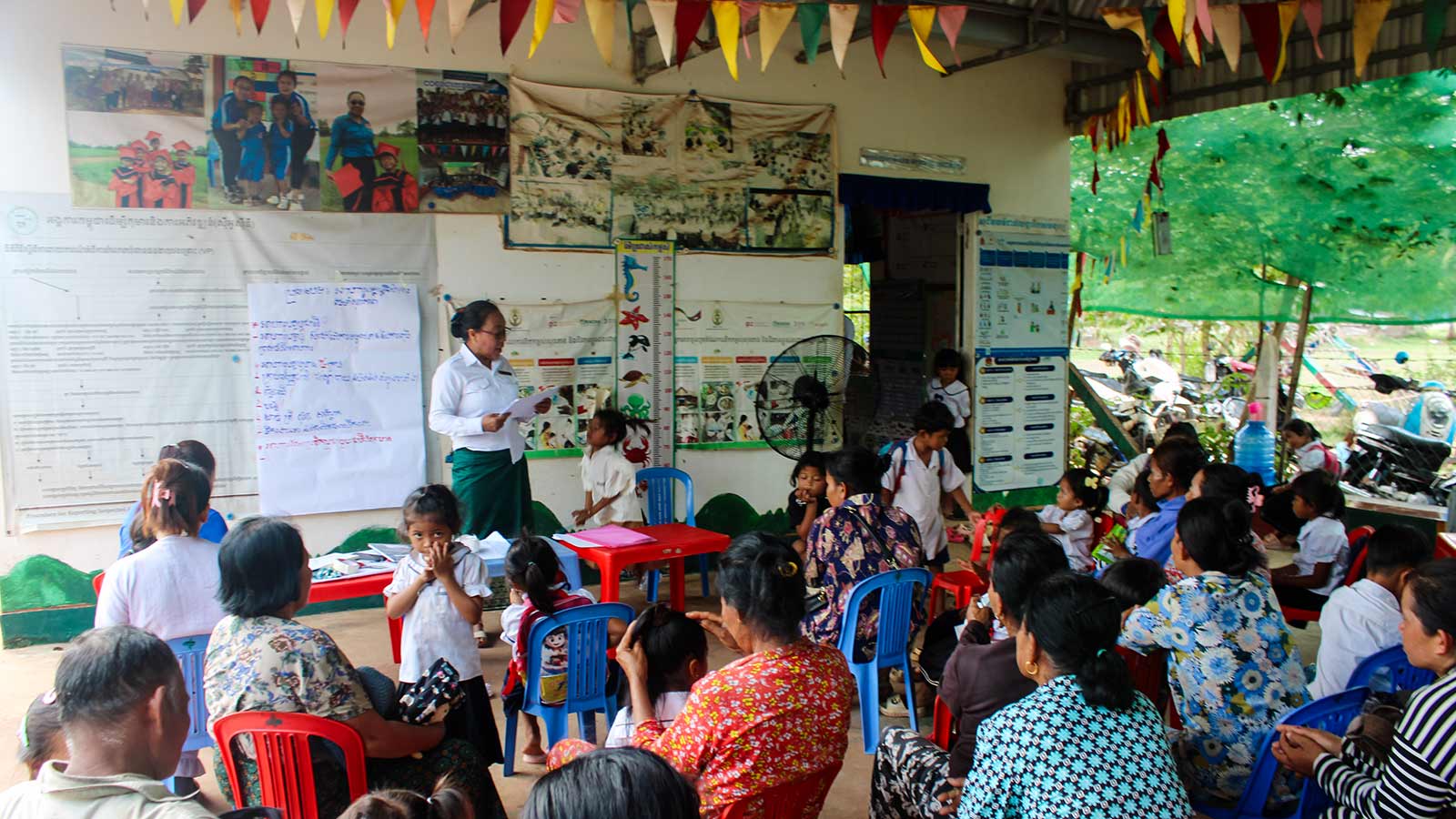 a group of families sit and listen to a community workshop in Cambodia