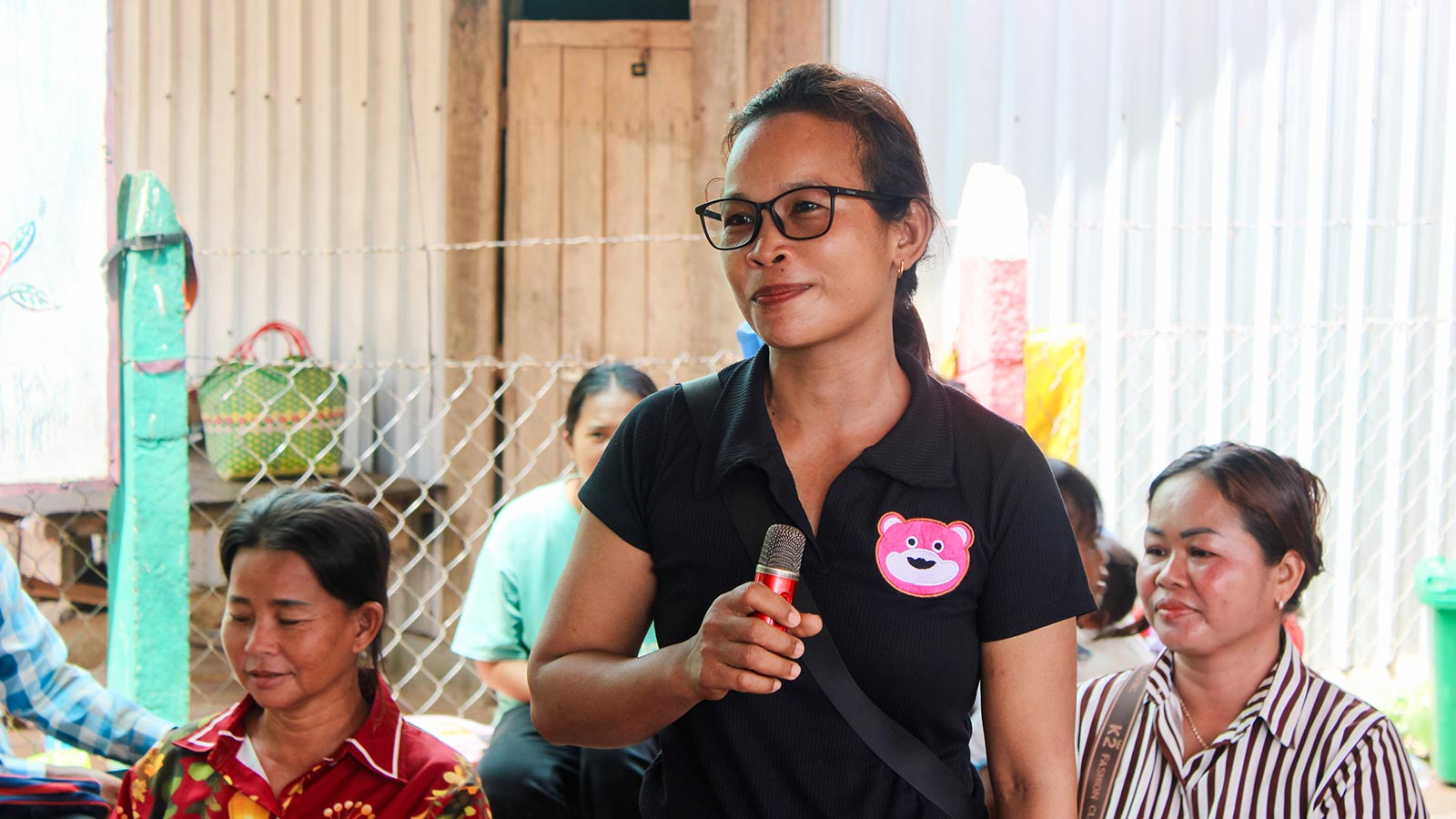 a woman holds a microphone at a community workshop in Cambodia