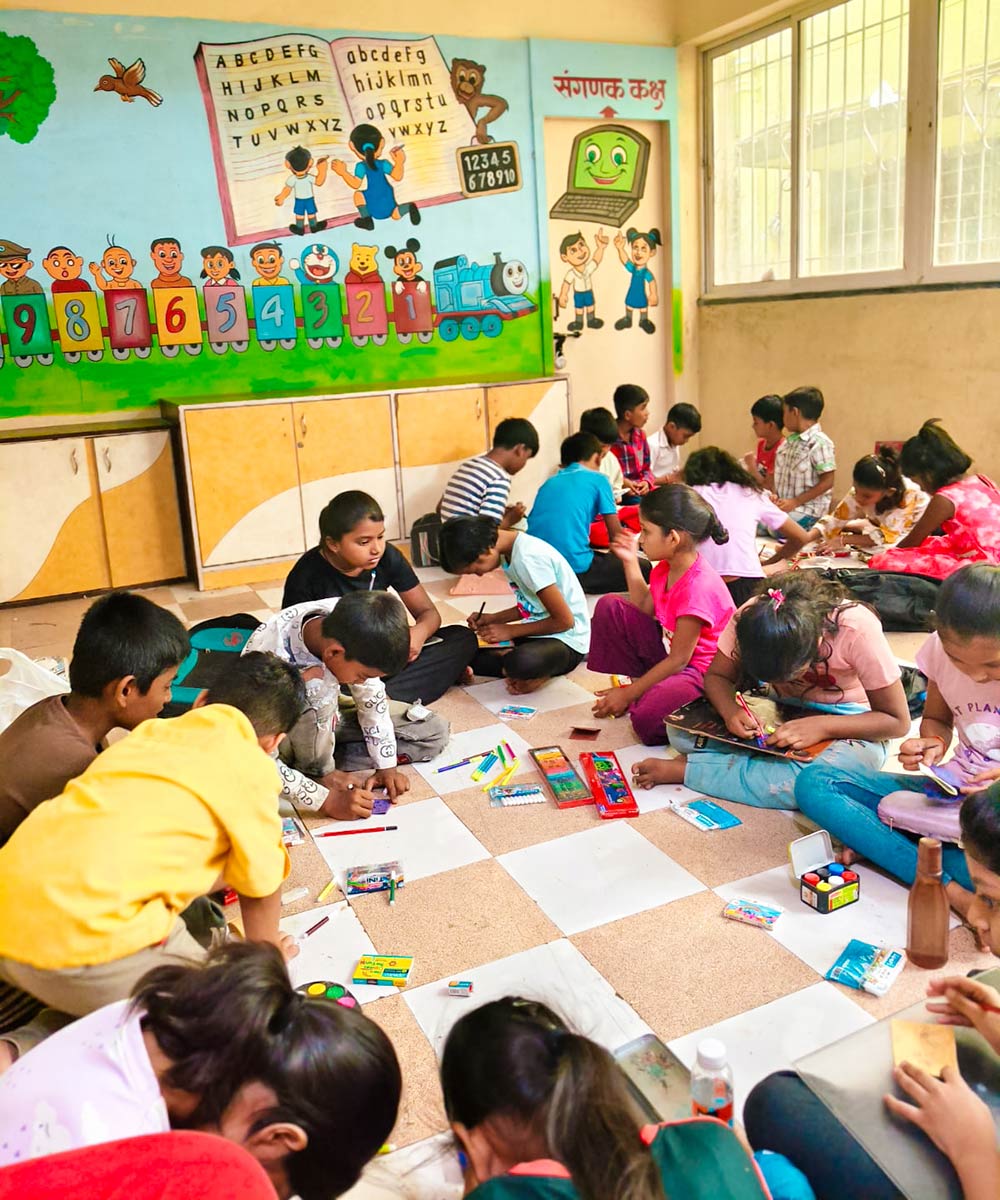 children sit in a circle on the floor and paint for summer camp in India
