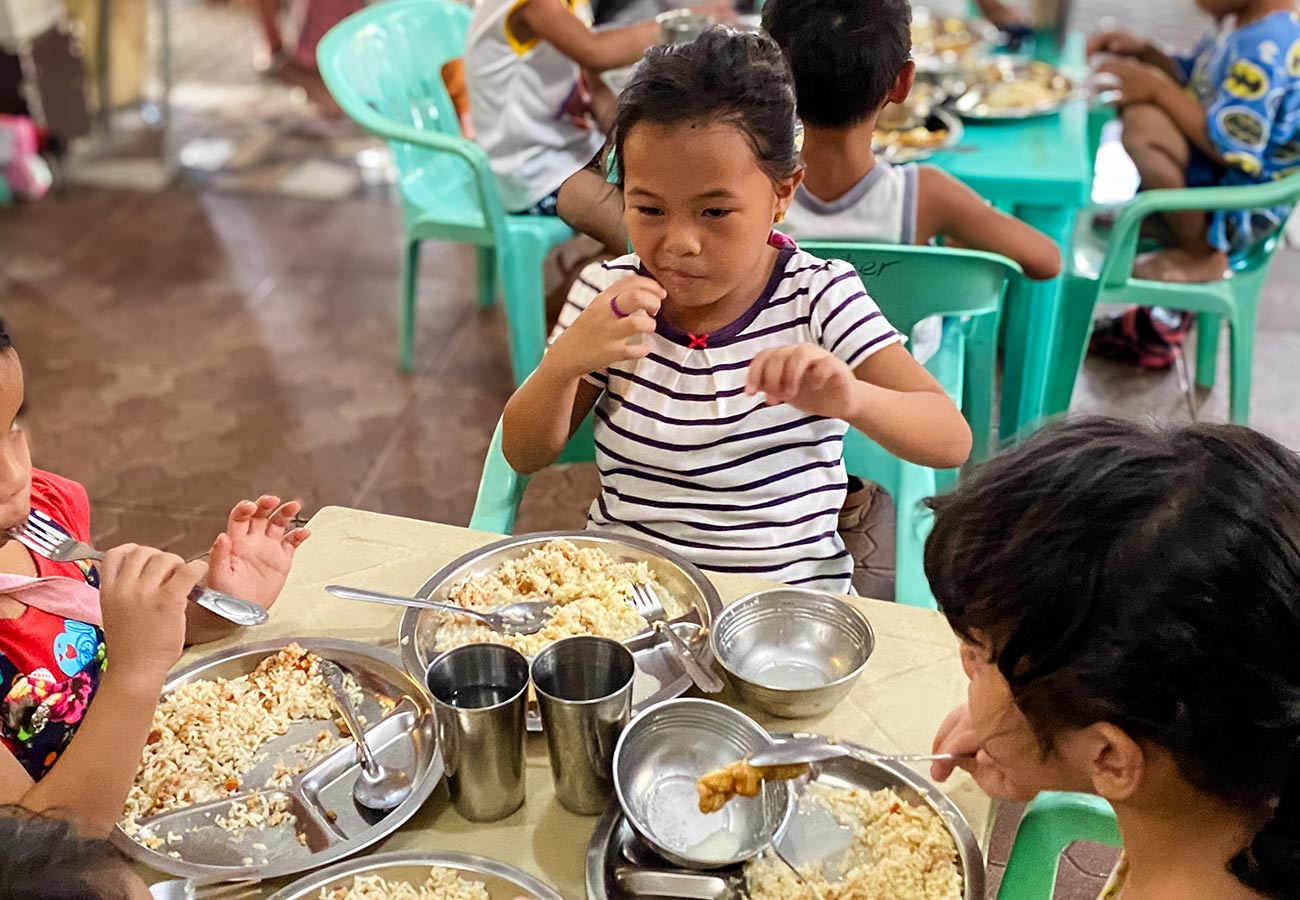 a group of children eat their lunch at a feeding center in the Philippines