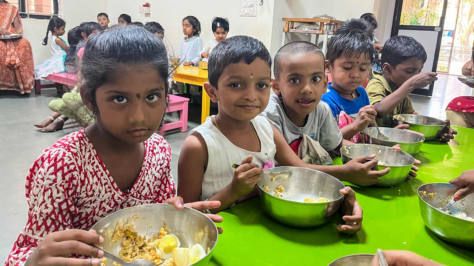 a group of children eat their school lunch at a daycare in India